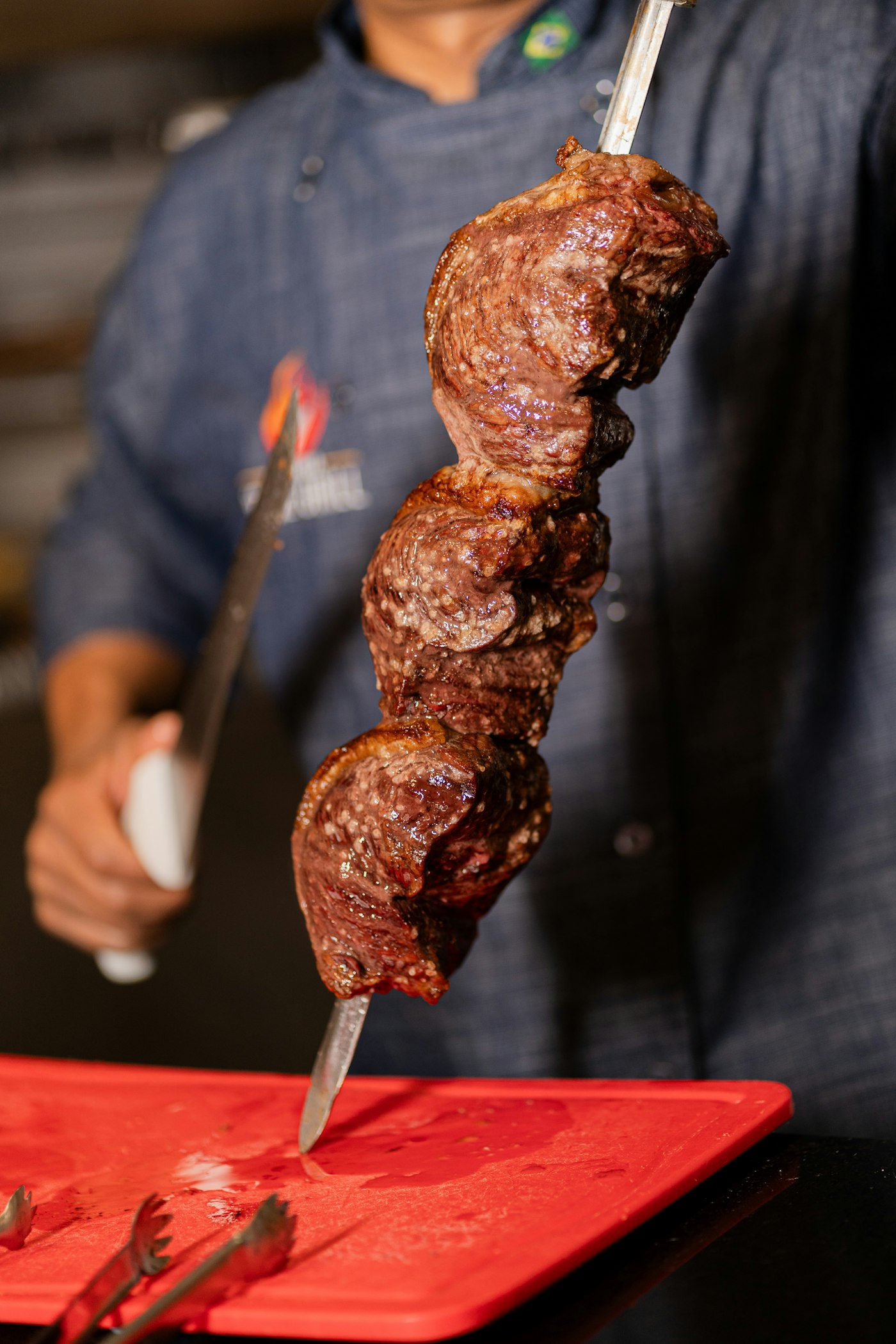 Assador cortando carne do espeto na mesa